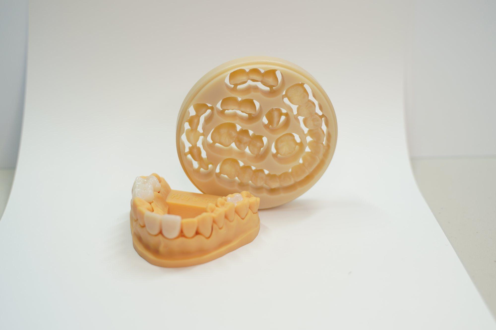 Zirconia disc with units cut from the blank, beside a dental model