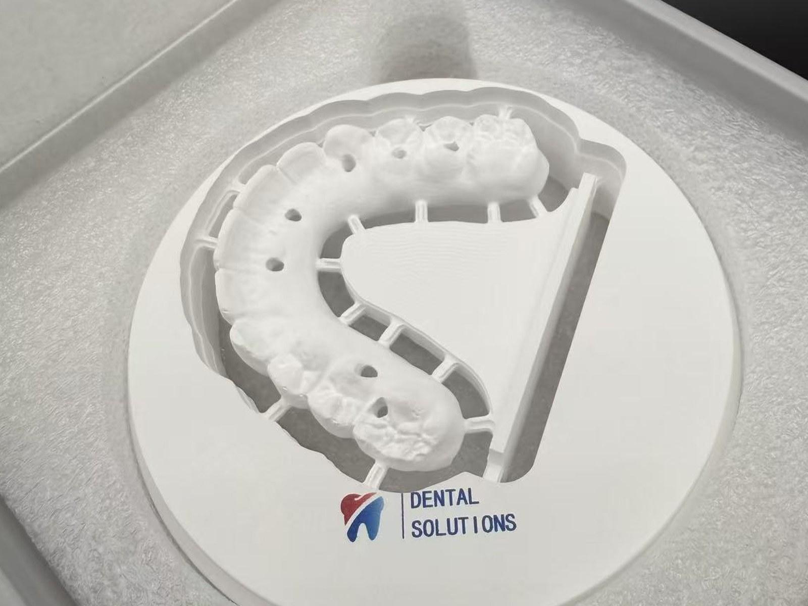 Milled full arch still held in its zirconia blank, in the disc box